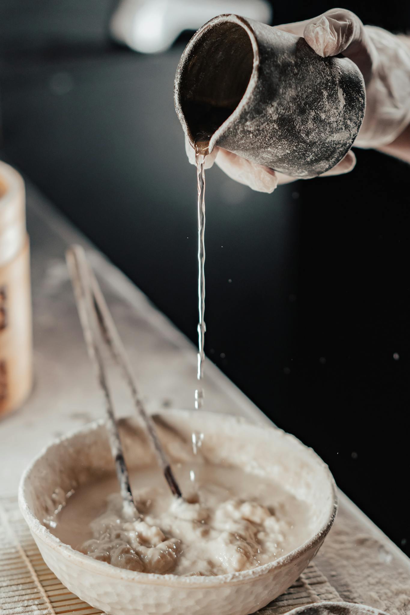 Close-up of water being poured into a bowl of dough, perfect for baking enthusiasts.