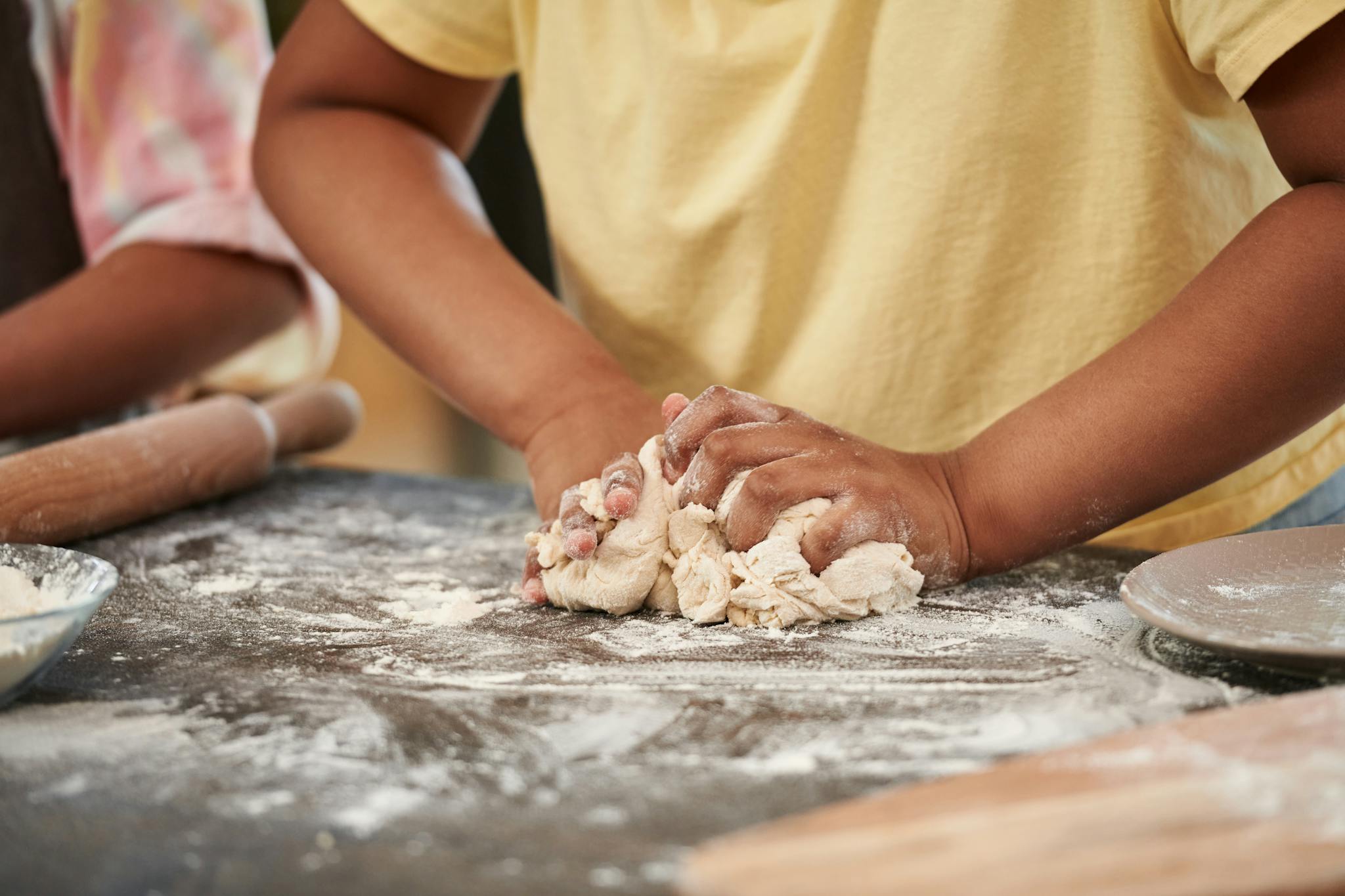 Hands kneading fresh dough on a floured surface, showcasing the art of baking indoors.