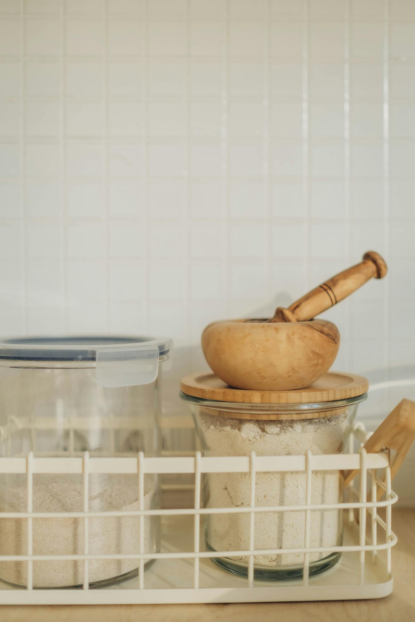 Organized kitchen setup with stored flour and a wooden mortar and pestle.
