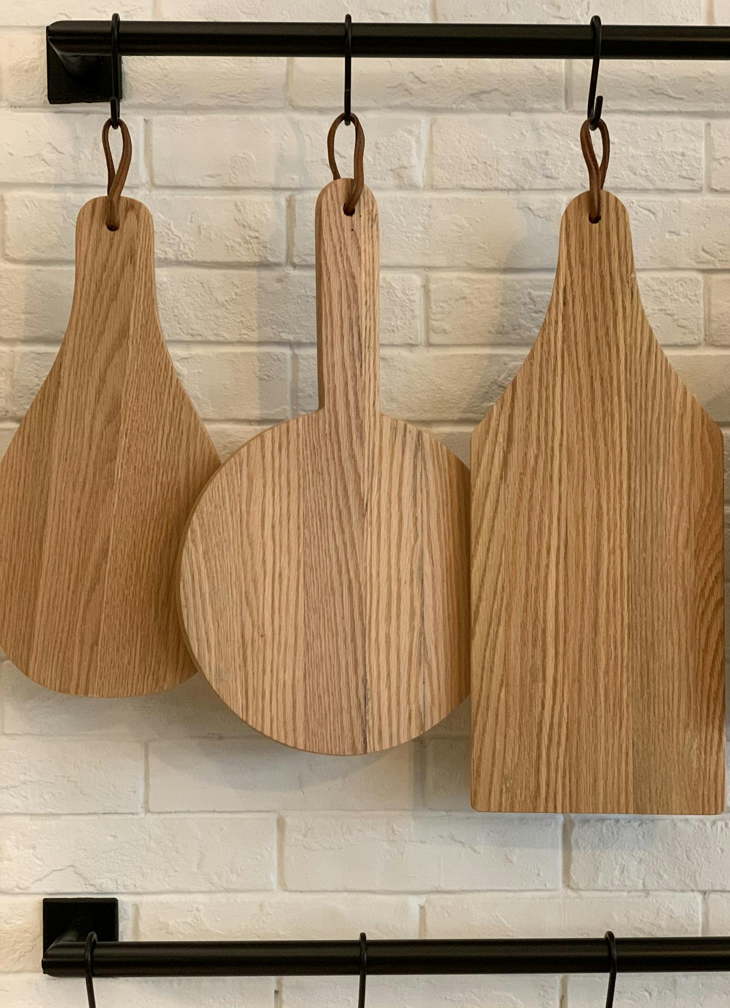 Three distinctive wooden cutting boards hanging on a kitchen wall for decorative and practical use.
