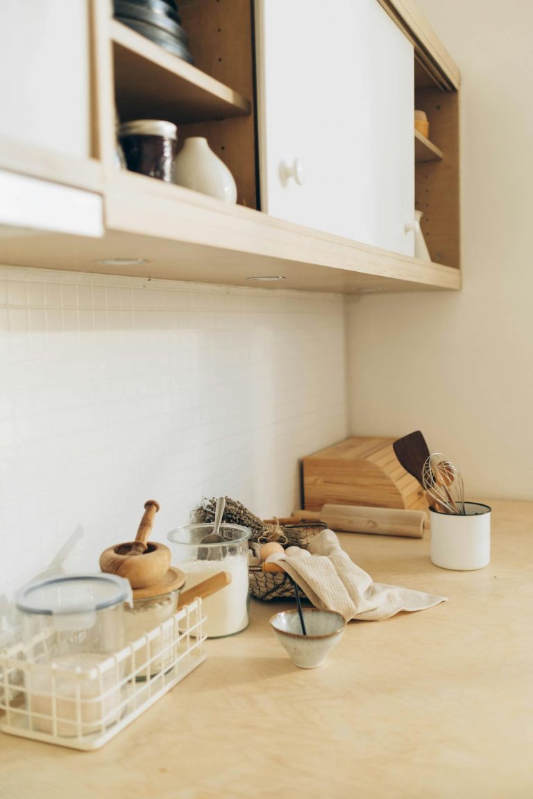 Warm, minimalist kitchen countertop with utensils and containers in natural light.